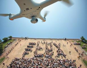 Picture Taken By A Drone Looking Down To Ground, Where Numerous People Are Organized To Form Word ”Flux”.  It Is Nice Summer Day.